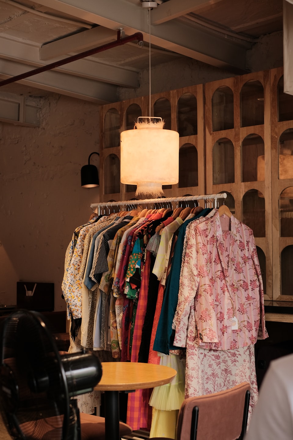 Vestiti colorati con motivi pendono da un appendiabiti in una boutique.